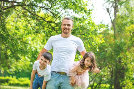 Happy beautiful family together father, son and daughter portrait on a walk on a Sunny summer dayの写真素材