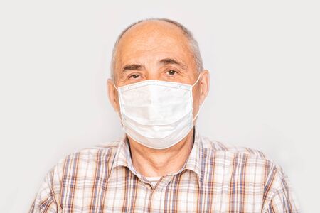 Portrait of a man an adult elderly pensioner in a medical mask on an isolated backgroundの写真素材