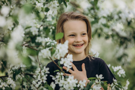 A sweet beautiful child girl against the background of blooming apple trees in the gardenの写真素材