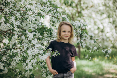 A sweet beautiful child girl against the background of blooming apple trees in the gardenの写真素材