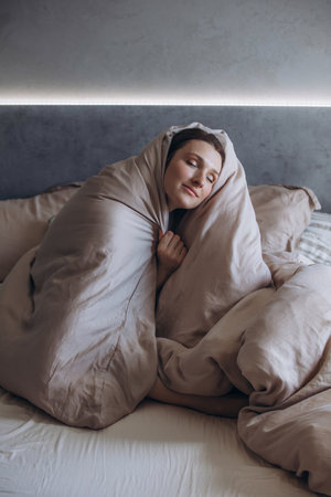 A beautiful brunette woman is resting on a bed in the bedroomの写真素材