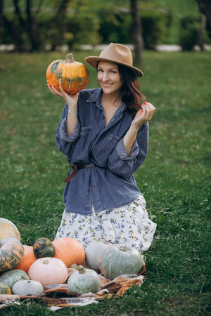 Woman is a young adult brunette in a straw hat with a pumpkin harvest on the street