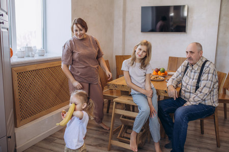 Grandma, grandpa and two granddaughters in the kitchen together happyの写真素材