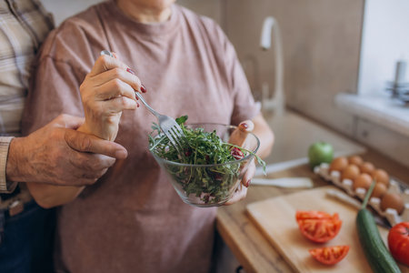Pensioners, man and woman, elderly people preparing salad together in kitchen, hands close-upの写真素材