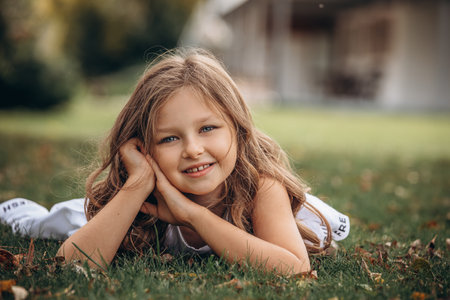 Beautiful child girl with white dress, portrait lying on the grassの写真素材
