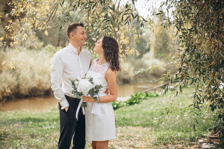 Beautiful happy couple married man and woman with a bouquet of flowers, portrait in natureの写真素材