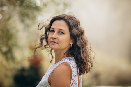 Beautiful young brunette woman in a white dress in nature, portraitの写真素材