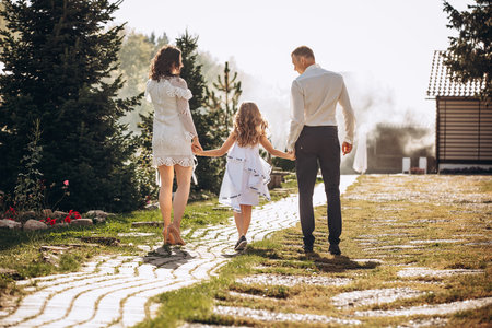 Family mother, father and daughter are beautiful and happy together, in white clothes, on a walkの写真素材