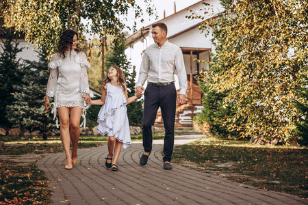 Family mother, father and daughter are beautiful and happy together, in white clothes, on a walkの写真素材