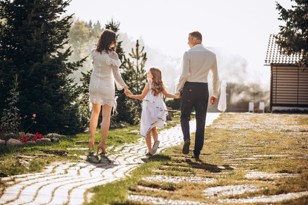 Family mother, father and daughter are beautiful and happy together, in white clothes, on a walkの写真素材