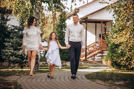 Family mother, father and daughter are beautiful and happy together, in white clothes, on a walkの写真素材