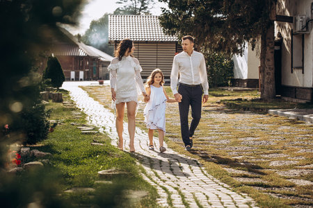 Family mother, father and daughter are beautiful and happy together, in white clothes, on a walkの写真素材