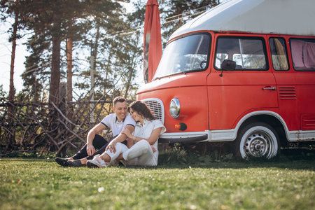 Beautiful happy couple in love man and woman, at the red bus trailerの写真素材