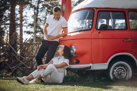 Beautiful happy couple in love man and woman, at the red bus trailerの写真素材