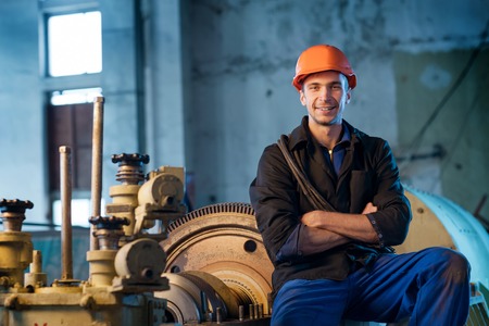 Portrait of a worker in the helmet near the turbine. Work the factory