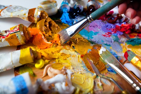 artist brush mix color oil painting on palette is holding in his hand closeupの写真素材
