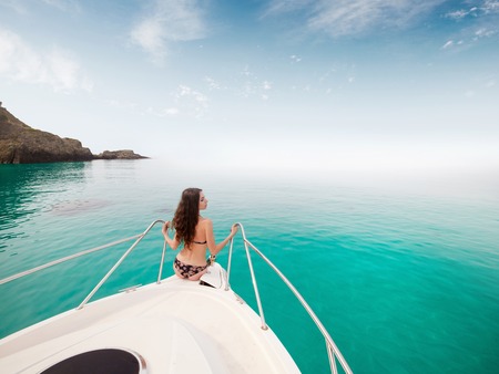 Beautiful young woman in bikini posing on a yacht at a sunny summer dayの写真素材