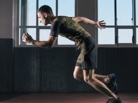 Young man fast running. Sports training in the gym.の写真素材