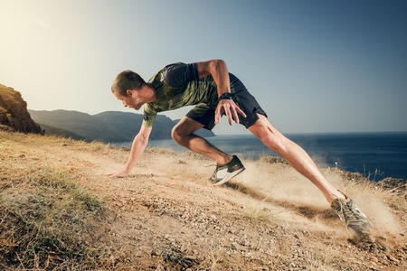 Young man runner running on a dusty country road. Jogger training workout in fitness shoe. Healthy lifestyle and sport concept.の写真素材