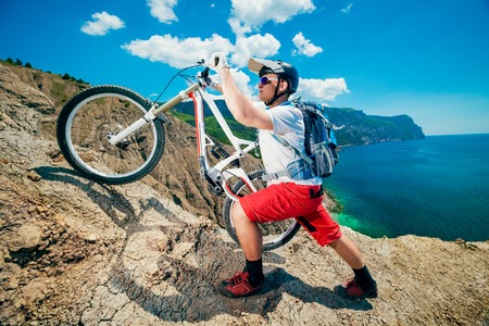 Man lifted the bike up the hill. Mountain Biking.Traveling by bicycle on the outdoors.の写真素材