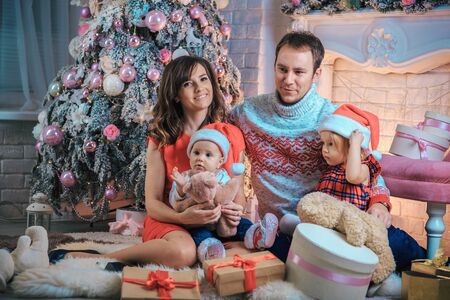 Christmas. Happy family with children near the Christmas tree with gifts. Portrait of mom, dad daughter and son Xmas night. New Year.の写真素材