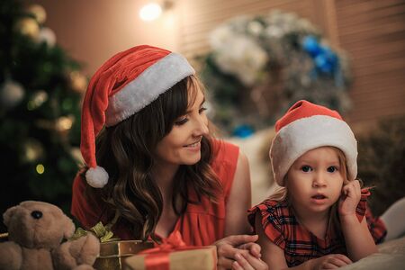 Happy family Mom with a daughter together on the background of Christmas decorations. Merry...