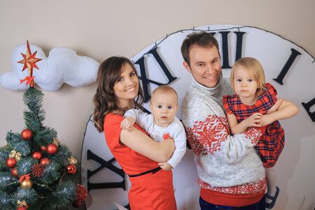 Happy family in the studio on the background of Christmas decorations. Parents with children are photographed near the Christmas tree together. New Year.の写真素材