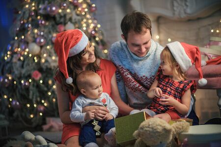 Happy young family celebrating christmas together. Parents with children near the Christmas tree. New Year. Happy Holidays! Xmas.の写真素材