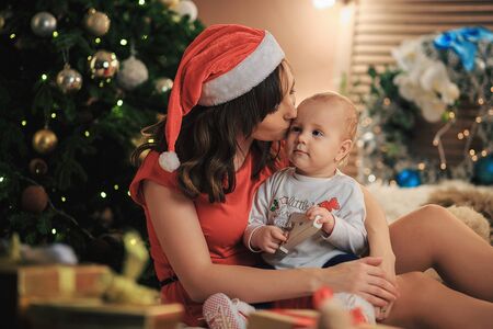 Happy family mother and baby little son playing in home near the decorated christmas tree. Christmas holidays. Portrait of mom and adorable baby celebrate Xmas. New Year.の写真素材
