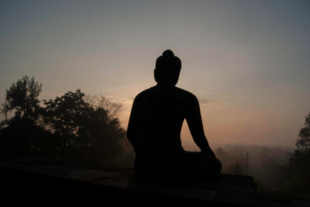 Sunrise behind a seated buddha statueの写真素材