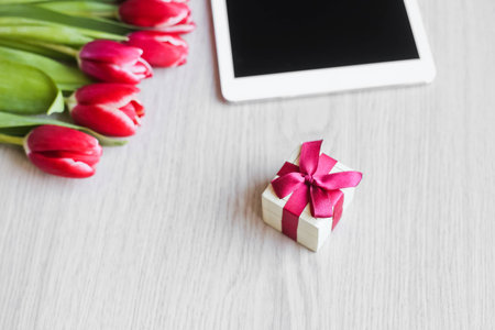 Red tulips, gift box with a red bow and tabletの写真素材