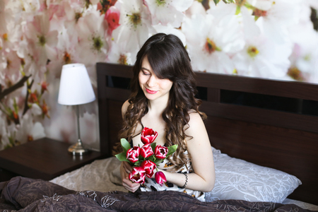 Girl with red flowers in the bedの写真素材