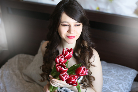 Girl with red flowers in the bedの写真素材