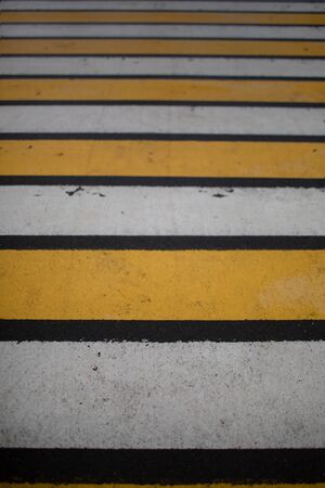 Pedestrian crosswalk-alternating white and yellow stripes on the asphalt for the safety of pedestrians on the roadsの写真素材