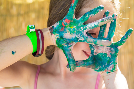 The hands of the child in the paint cover the faceの写真素材