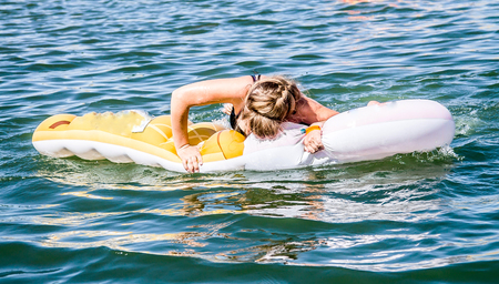 Woman on an inflatable mattress on the water in the sea -  A woman tries to climb on an inflatable mattress on the water in the seaの写真素材