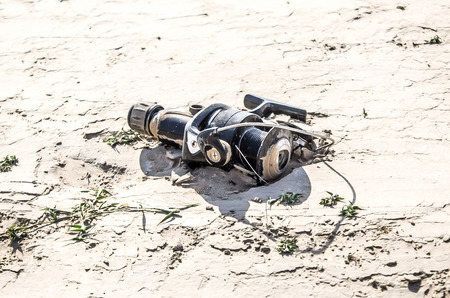 Old fishing spinning reel in the sandの写真素材