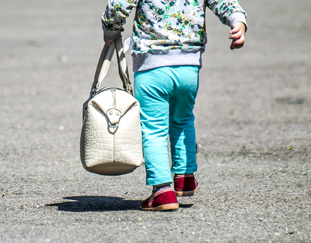 A child with her mother's bag in the parkの写真素材
