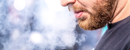 A man with a beard blowing smokeの写真素材
