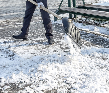 Cleaning the snow in a hand shovel in the parkの写真素材