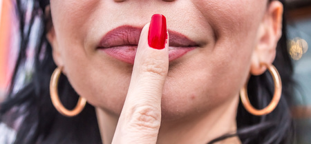 Girl covers her mouth with his hand with a red manicureの写真素材