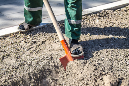 A worker digs the earth with a shovelの写真素材