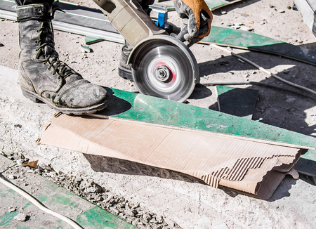 A worker cutting ceramic granite tiles with a power toolの写真素材