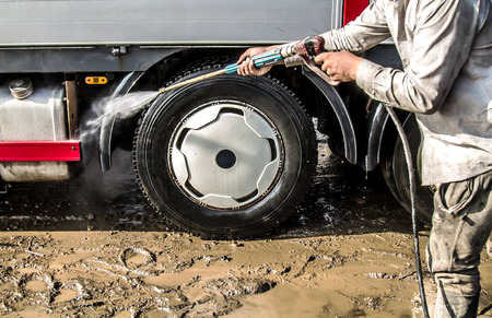 A man washing big truck with a hoseの写真素材