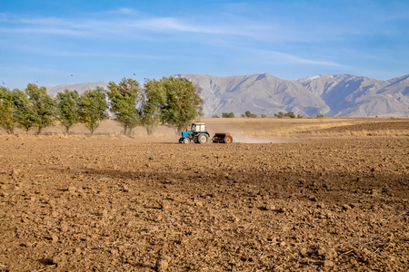 Tractor with a seeder on a fieldの写真素材