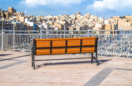 Lonely bench on the embankment on the background of the old stone city in Maltaの写真素材