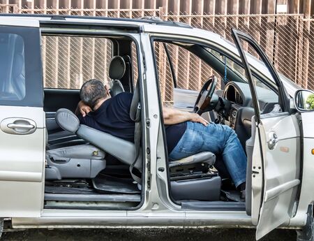 The driver of the car sleeps in the carの写真素材