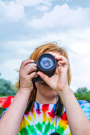 Woman photographer with a camera takes pictures against the skyの写真素材