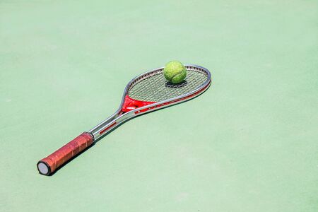 Tennis ball and racket on an artificial courtの写真素材