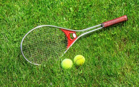 Tennis ball and racket on the green grass of the court close-up